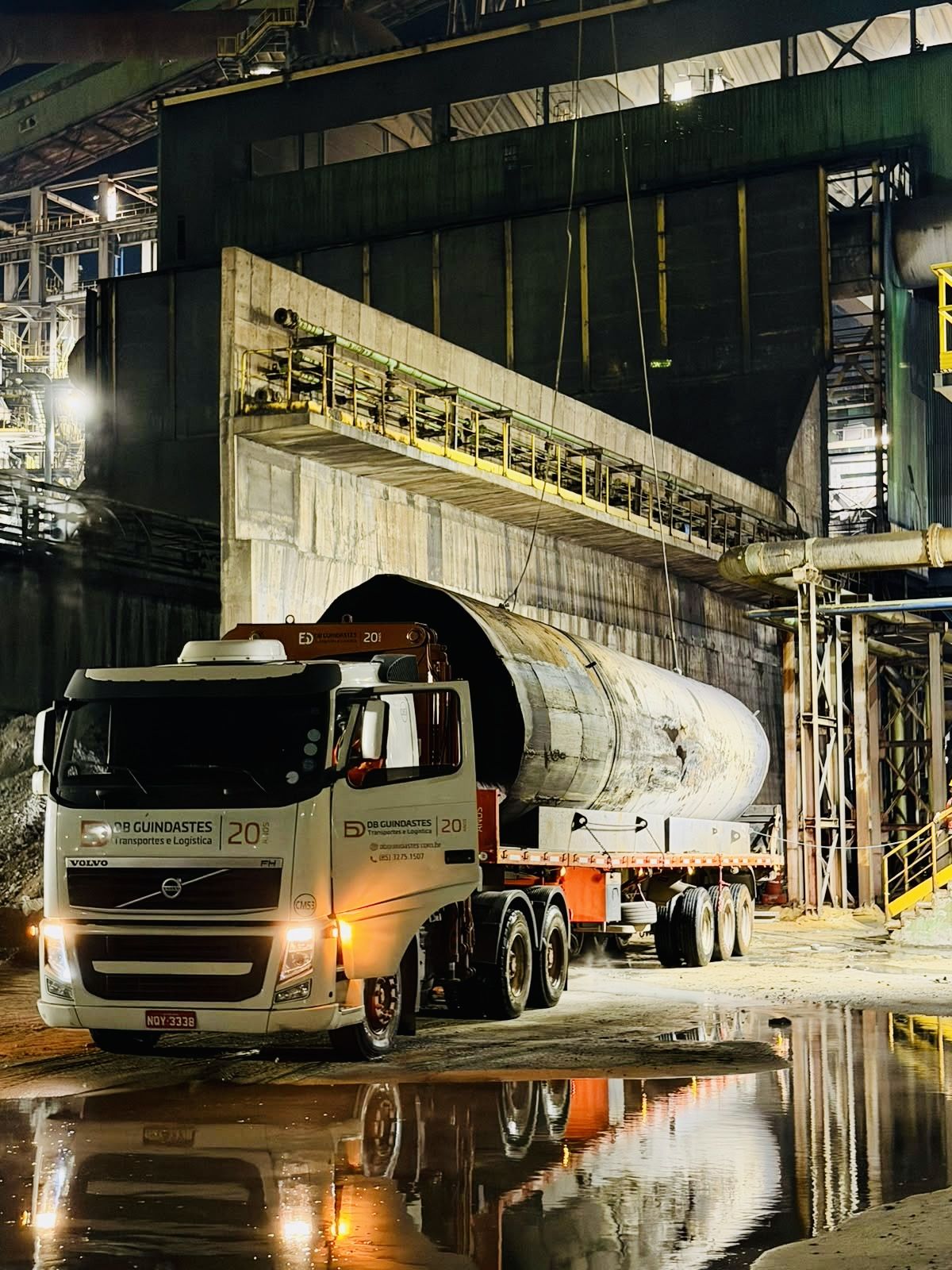 Caminhão da DB Guindastes transportando carga de grande porte à noite.